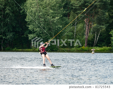 Wake boarding  boy on lake, the forest in blurry background. 81725543