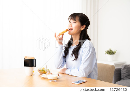 Woman eating bread at breakfast Woman eating bread at breakfast 81726480