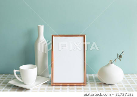 Photo frame and white coffee cup, vase on mosaic tile table. mint wall background. home interior Photo frame and white coffee cup, vase on mosaic tile table. mint wall background. home interior 81727182