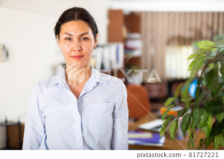 Positive confident Asian businesswoman standing in modern office Positive confident Asian businesswoman standing in modern office 81727221