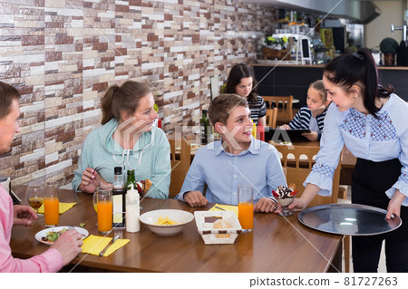 Young brunette waitress serving large family in family cafe Young brunette waitress serving large family in family cafe 81727263