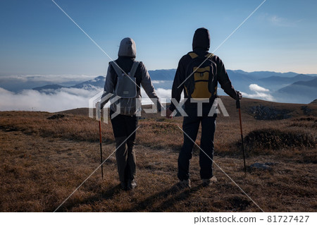 woman and man in nature wearing hiking backpacks and sticks. 81727427