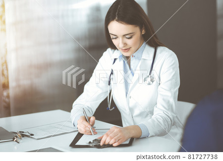 Friendly young woman-doctor is listening to her patient, while sitting together in sunny clinic. Medicine and healthcare concepts Friendly young woman-doctor is listening to her patient, while sitting together in sunny clinic. Medicine and healthcare concepts 81727738