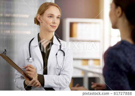 Friendly smiling female doctor and patient woman discussing current health examination in sunny clinic. Perfect medical service in hospital. Medicine concept Friendly smiling female doctor and patient woman discussing current health examination in sunny clinic. Perfect medical service in hospital. Medicine concept 81727888