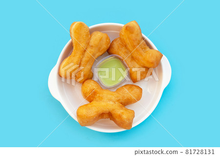 Deep-fried dough sticks or chinese bread sticks on blue background. Deep-fried dough sticks or chinese bread sticks on blue background. 81728131