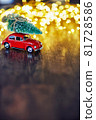 A festive New Year card with a space for text, sparkling lights, golden glitter, defocused lights and a red car on dark brown wooden background 81728586