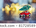A festive New Year card with a space for text, sparkling lights, golden glitter, defocused lights and a red car on dark brown wooden background 81728589