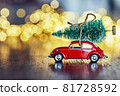 A festive New Year card with a space for text, sparkling lights, golden glitter, defocused lights and a red car on dark brown wooden background 81728592