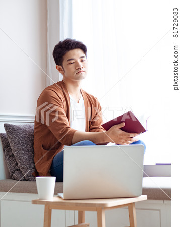 年輕的亞洲男人在家放鬆時看書 年輕的亞洲男人在家放鬆時看書 81729083