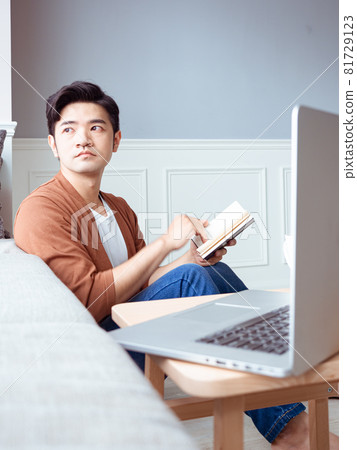 Young Asian man reading book while relaxing at home Young Asian man reading book while relaxing at home 81729123