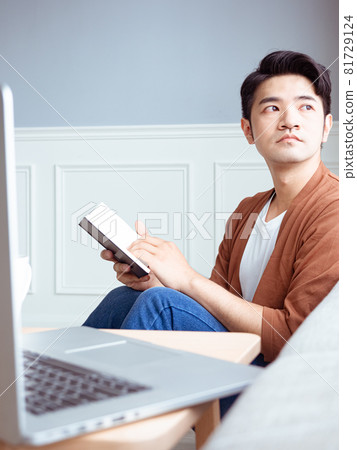 年輕的亞洲男人在家放鬆時看書 年輕的亞洲男人在家放鬆時看書 81729124