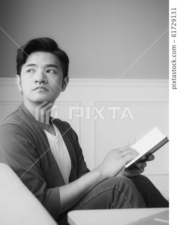 年輕的亞洲男人在家放鬆時看書 年輕的亞洲男人在家放鬆時看書 81729131