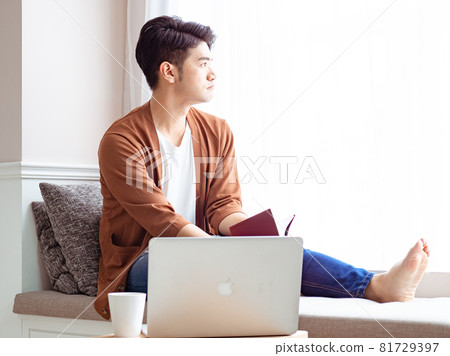 Young Asian man reading book while relaxing at home Young Asian man reading book while relaxing at home 81729397