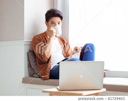 Young Asian man reading book while relaxing at home Young Asian man reading book while relaxing at home 81729401