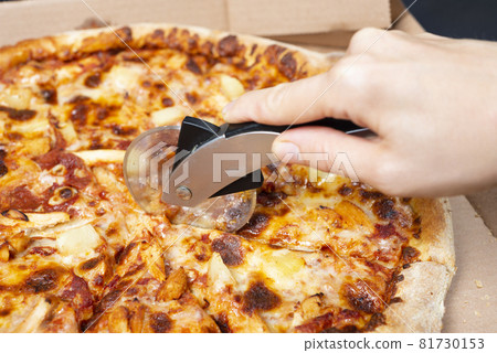 Close up on hand cutting pizza with pizza knife Tasty paperoni pizza in open box isolated on black background. Top view on paperoni pizza. Concept for italian food, street food, fast food, quick bite. Close up on hand cutting pizza with pizza knife Tasty paperoni pizza in open box isolated on black background. Top view on paperoni pizza. Concept for italian food, street food, fast food, quick bite. 81730153