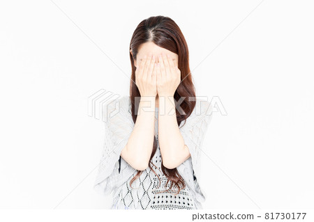 A woman in casual clothes hiding her face with her hands 81730177
