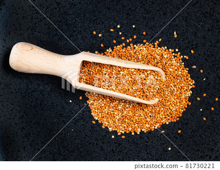 top view of wood scoop on pile of chumiza siberian millet seeds on black plate top view of wood scoop on pile of chumiza siberian millet seeds on black plate 81730221
