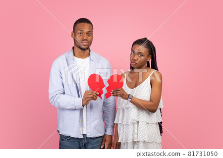 Disappointed couple holding two pieces of broken paper heart Disappointed couple holding two pieces of broken paper heart 81731050
