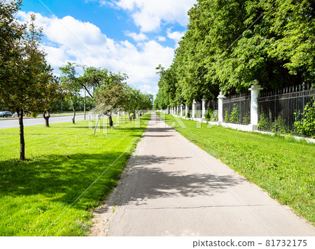 pedestrian pathway with green lawn and apple trees along Moscow State University garden on street Prospekt Vernadskogo in Moscow city in sunny summer day 81732175