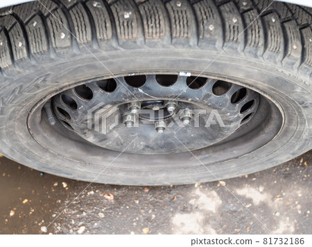 top view of attached used studded winter tire on car during for seasonal replacement of wheels 81732186