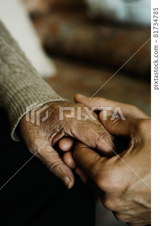 young man holds the hand of an old woman 81734785