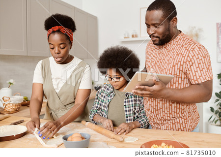 Young African family of three cooking homemade pastry 81735010
