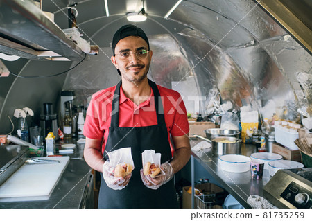 Gloved young man in uniform holding fast food Gloved young man in uniform holding fast food 81735259