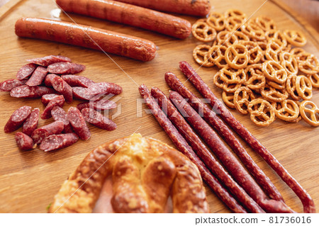 Close-up beer snacks, smoked sausages and pretzels on wooden tray. Top view. Oktoberfest holiday cuisine. Traditions, fun, joy, food and drinks. 81736016