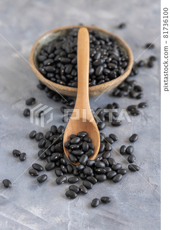 Wooden scoop full of dry black beans on grey table closeup Wooden scoop full of dry black beans on grey table closeup 81736100