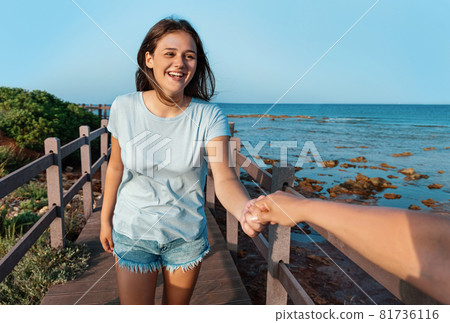 Happy teenage girls running on sidewalk by the sea at sunset Happy teenage girls running on sidewalk by the sea at sunset 81736116