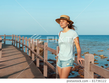 Teen girl standing on wooden bridge by the sea Teen girl standing on wooden bridge by the sea 81736122