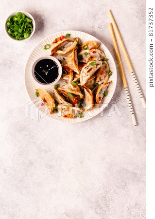Fried dumplings served with green onions, sesame seeds and chili peppers 81737352