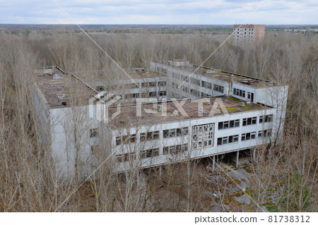An abandoned concrete building among the trees in Pripyat. Aerial view. Cloudy weather, landscape. 81738312