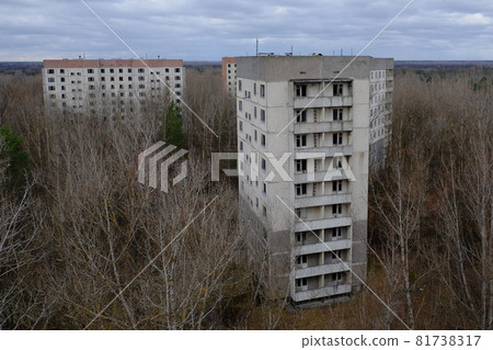 Abandoned panel houses among leafless trees in Pripyat. Beautiful cloudy sky over the city. Post-Soviet architecture. 81738317