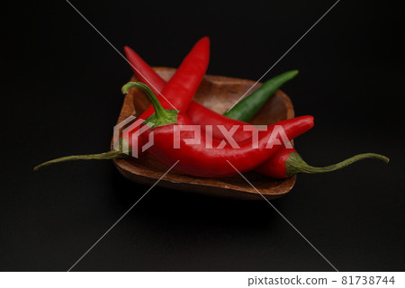 Chili peppers on wooden over a black background Chili peppers on wooden over a black background 81738744