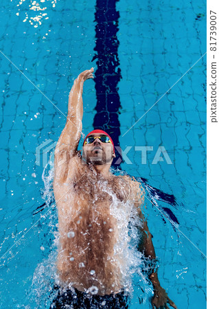 Young professional male swimmer practicing and training at pool, indoors. Healthy lifestyle, power, energy, sports movement concept 81739007