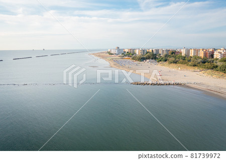 Drone view of sandy beach with umbrellas and town background Drone view of sandy beach with umbrellas and town background 81739972