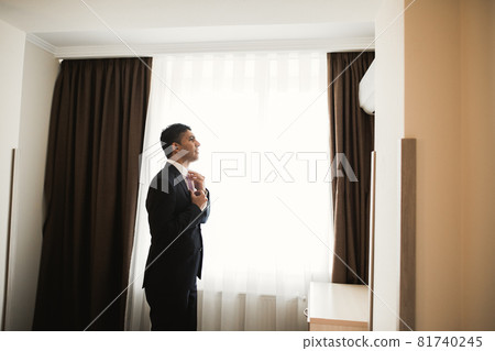 Grooms morning preparation. Handsome man getting dressed and preparing for the wedding 81740245