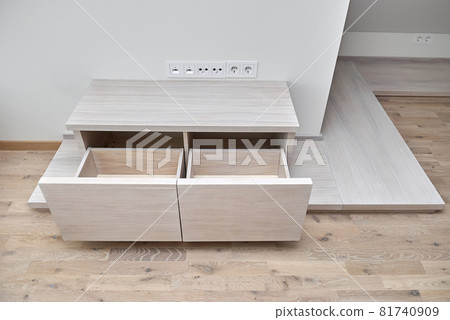Commode for TV set of white oak lumber with open drawers on a wooden podium Commode for TV set of white oak lumber with open drawers on a wooden podium 81740909