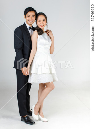 Young attractive Asian couple, bride and groom, woman wearing white wedding dress. Man wearing black tuxedo, standing together. Concept for pre wedding photography 81746910