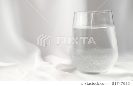 a glass of sparkling mineral water white silk background. water drinking, morning rituals, trendy styled composition 81747623