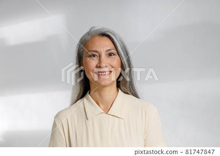 Portrait of pretty grey haired woman in beige blouse on light background Portrait of pretty grey haired woman in beige blouse on light background 81747847