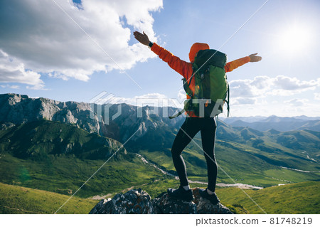 Successful woman backpacker hiking on alpine mountain peak 81748219