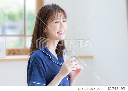 Young woman drinking mineral water in pajamas 81748495