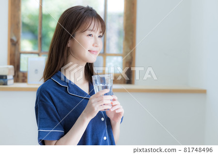 Young woman drinking mineral water in pajamas Young woman drinking mineral water in pajamas 81748496