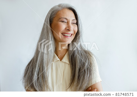 Portrait of smiling Asian woman with hoary hair and crossed arms on grey background Portrait of smiling Asian woman with hoary hair and crossed arms on grey background 81748571