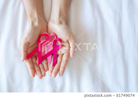 October Breast Cancer Awareness month, adult Woman  hand holding Pink Ribbon on pink background for supporting people living and illness. International Women, Mother and World cancer day concept 81749074