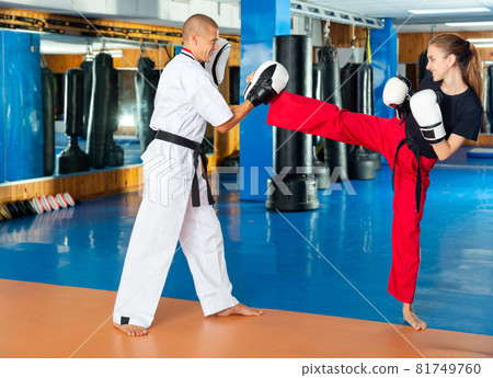 Young woman practicing boxing punches in pair with instructor Young woman practicing boxing punches in pair with instructor 81749760