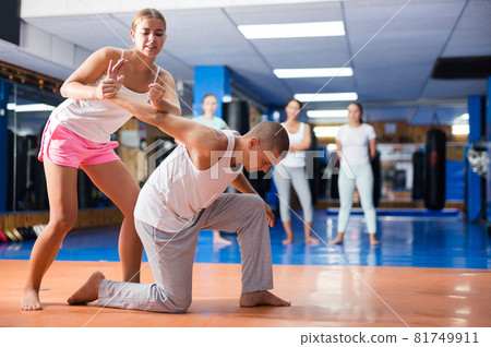 Girl performing hammerlock to male opponent during self defence training in gym 81749911