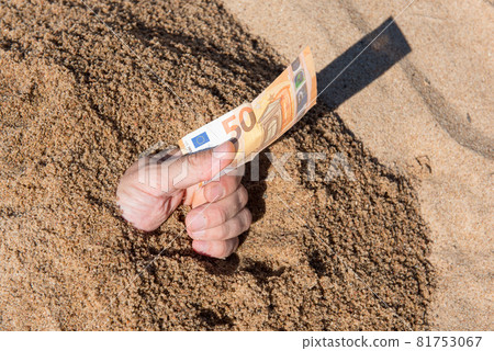 Fifty euros in the hand of a man sticking out of the sand Fifty euros in the hand of a man sticking out of the sand 81753067